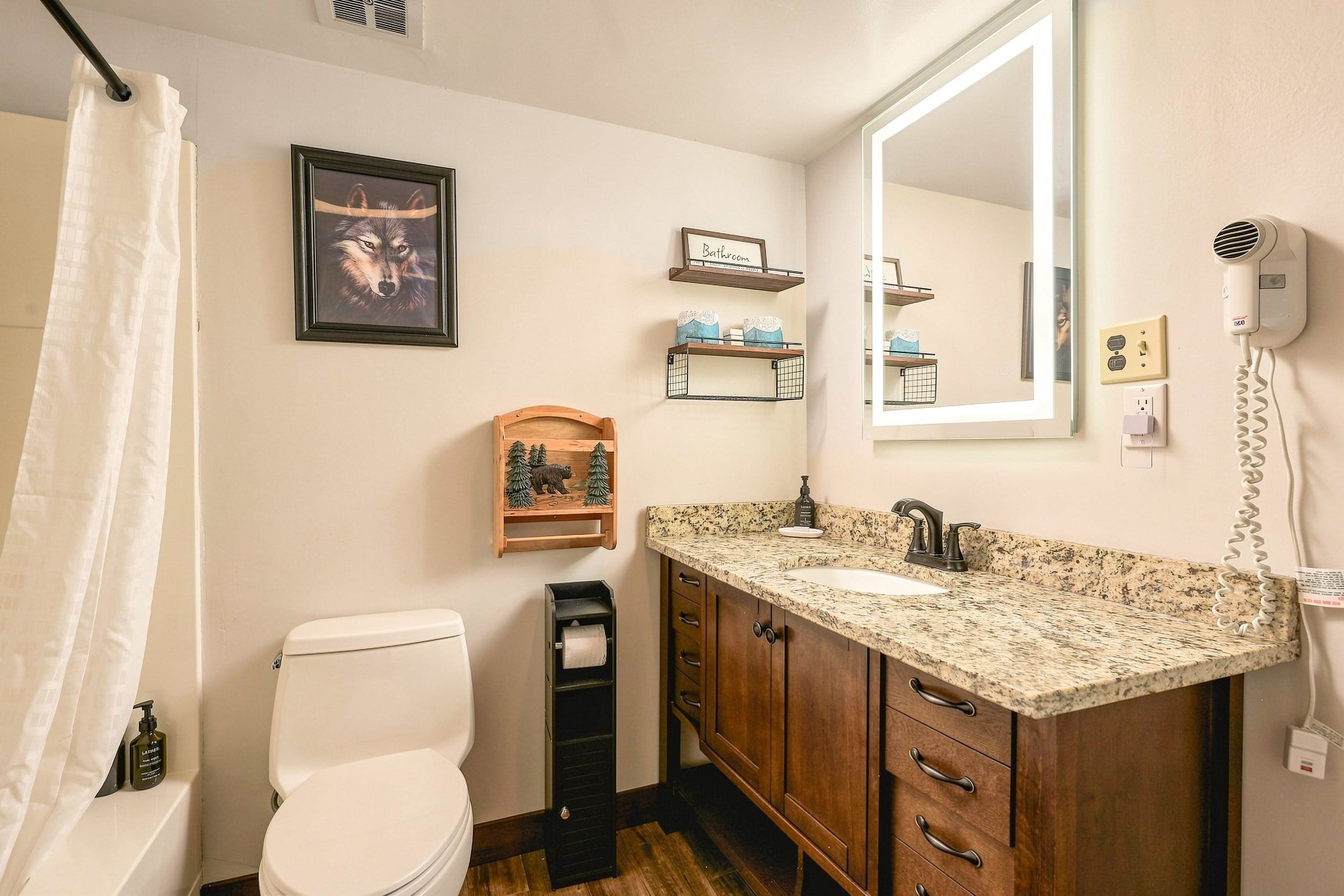 A bathroom with a toilet, sink, vanity, and a mirror.