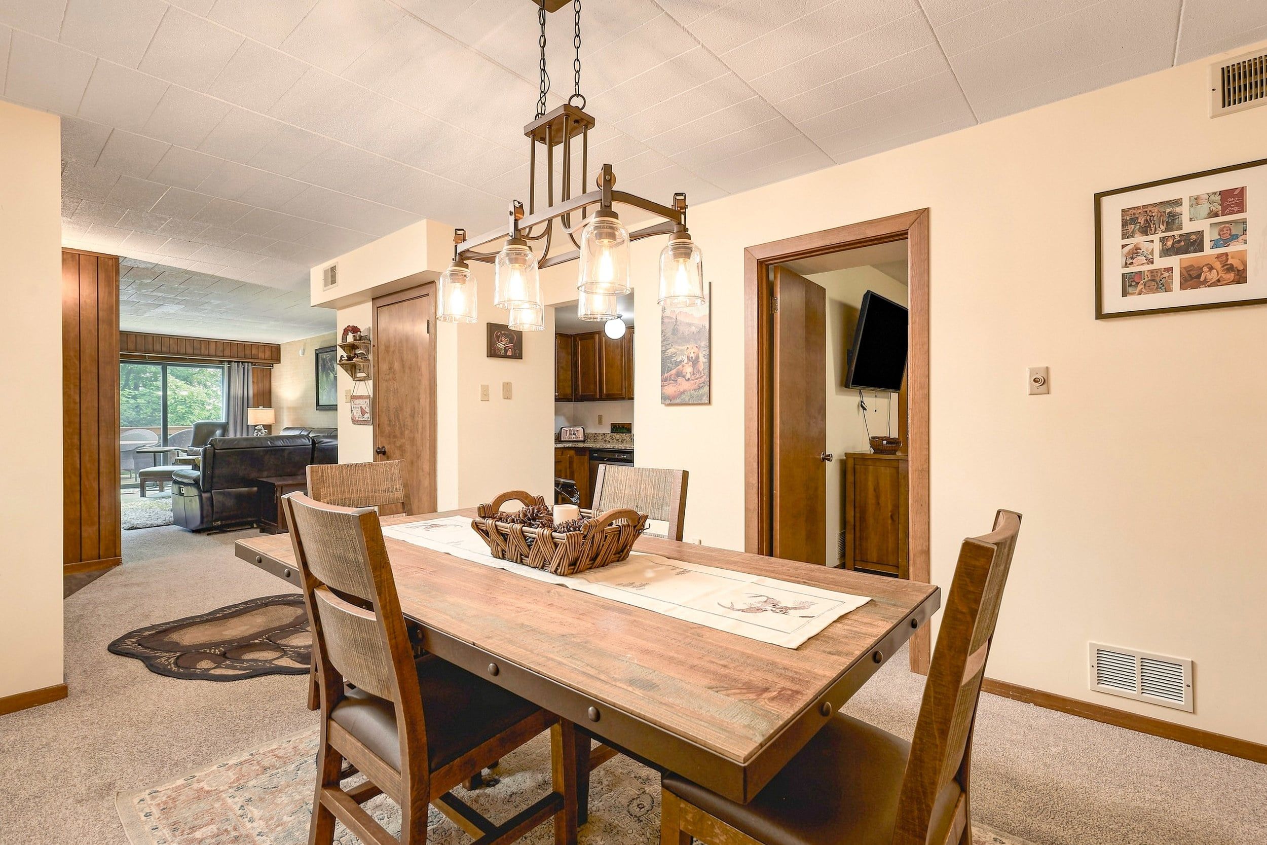 Uma sala de jantar com mesa de madeira, cadeiras e lustre.