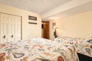 A bedroom with two beds, a door, a wall-mounted light, and a framed picture.