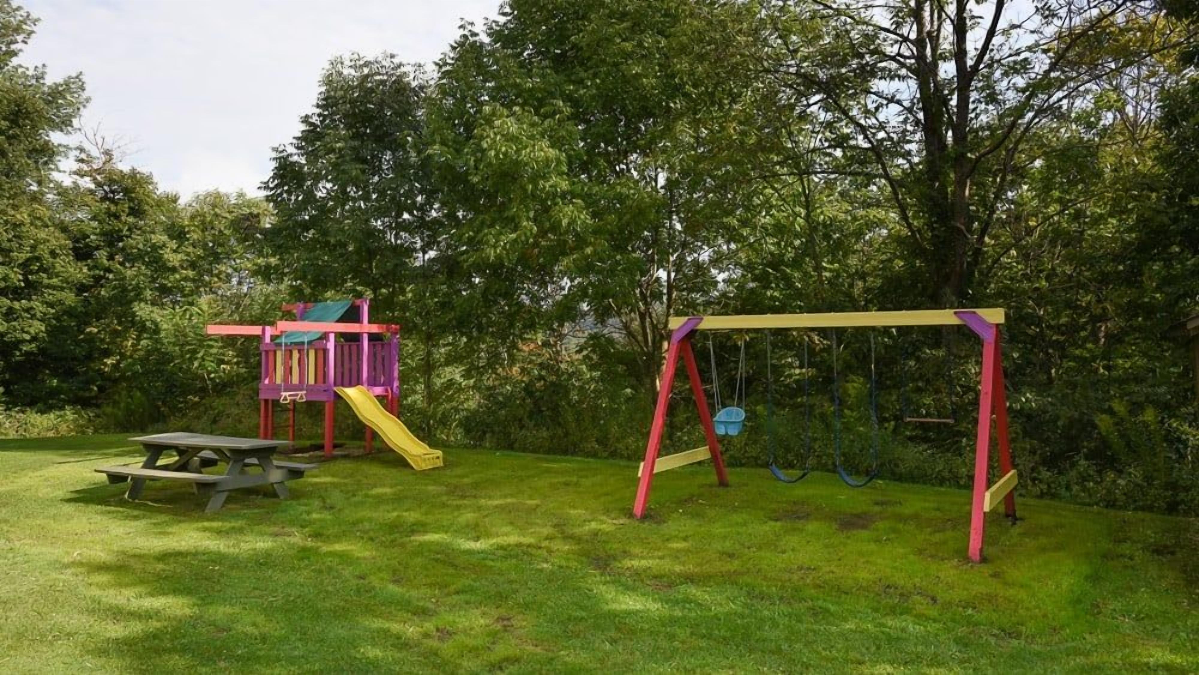 Un parque infantil con columpios y un tobogán.