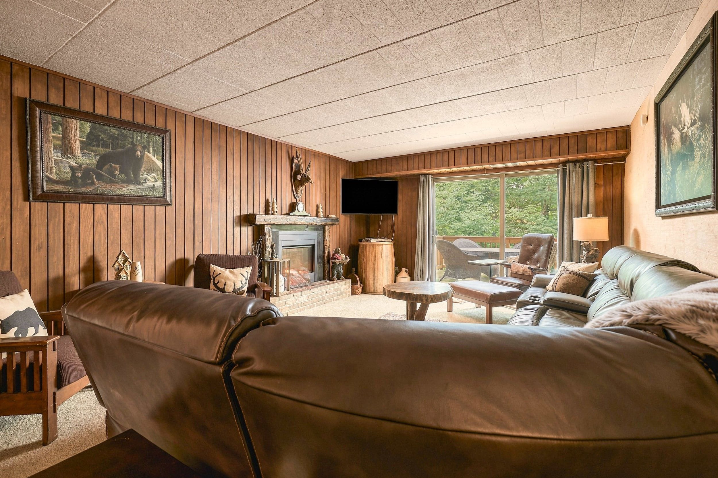 A cozy living room with a fireplace, leather sofa, and a television.