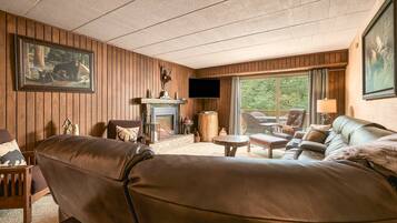 A cozy living room with a fireplace, leather sofa, and a television.