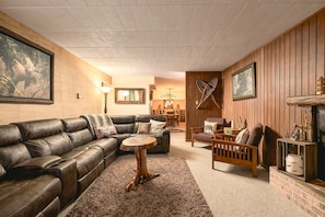 A cozy living room with a leather sofa, a round coffee table, and a fireplace.