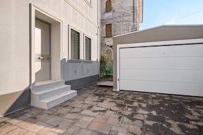 Ein Wohngebäude mit Garage, einer Treppe zum Eingang und einem kleinen Garten.