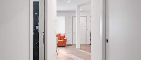 A modern interior with a wooden floor, a white door, and a bright room with a window.