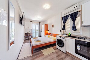 A modern bedroom with a bed, washing machine, and kitchenette. - S1 - Studio just 50m from the beach with sea view (Korčula)