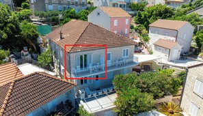 A residential building with a tiled roof, a balcony with white railings, and a small garden area. - S1 - Studio just 50m from the beach with sea view (Korčula)