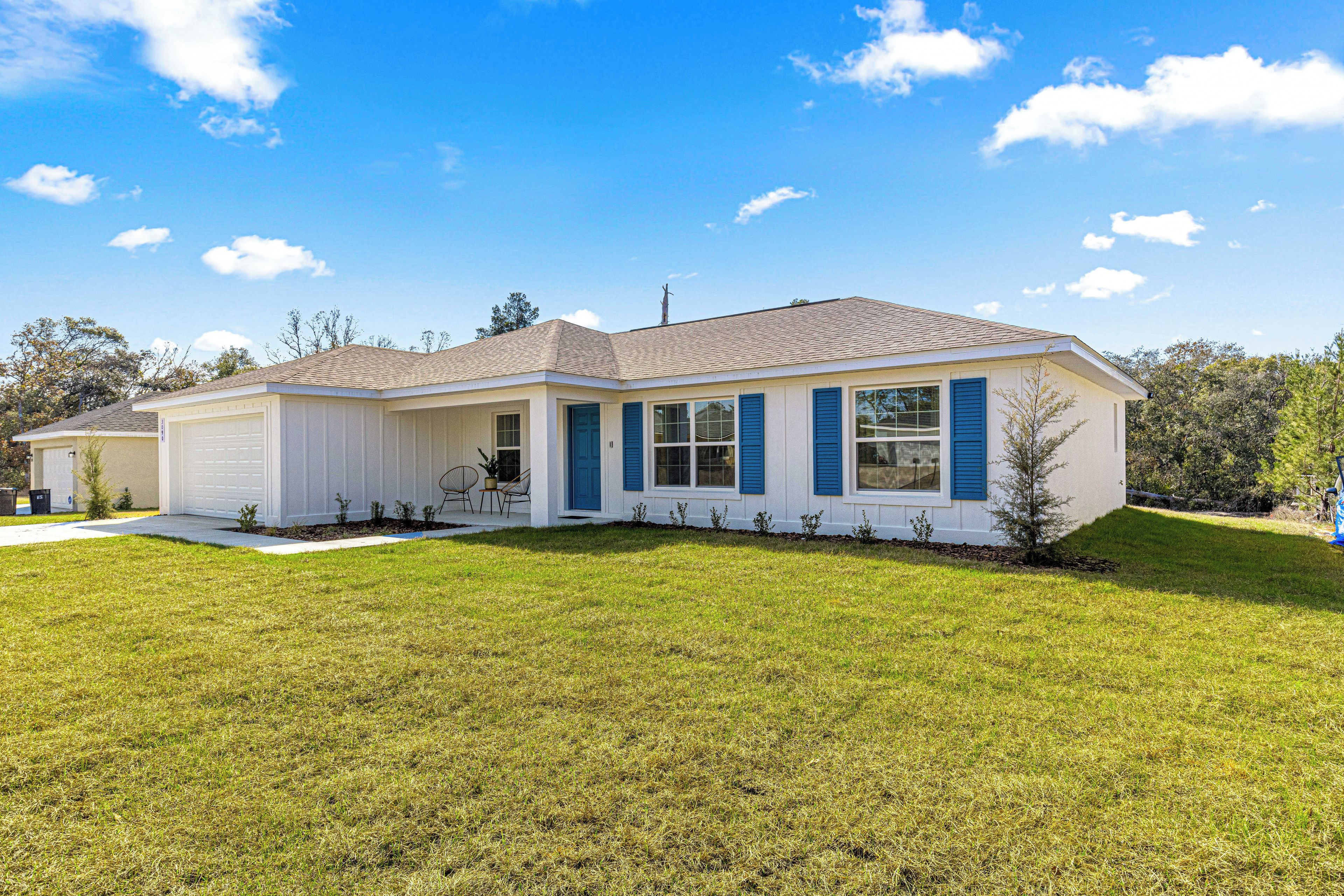 A single-story house with a garage, a covered porch, and a well-maintained lawn.