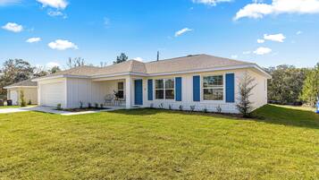 A single-story house with a garage, a covered porch, and a well-maintained lawn.