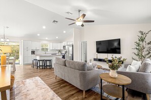 A modern living room with a grey sofa, a coffee table, and a TV mounted on the wall. - Spacious 4-bedroom home, minutes from I-75 with a game room and sleeping for 8! (Ocala)