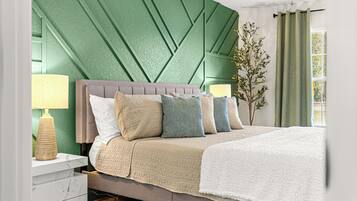 A modern bedroom with a green textured wall, a grey upholstered headboard, and a white bedspread.