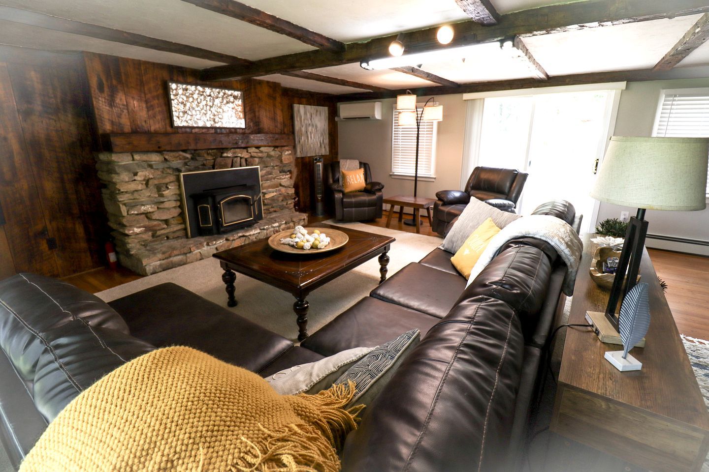 Ein gemütliches Wohnzimmer mit Kamin aus Stein, einer Ledersofa und einem Couchtisch mit einer Schale Kekse.
