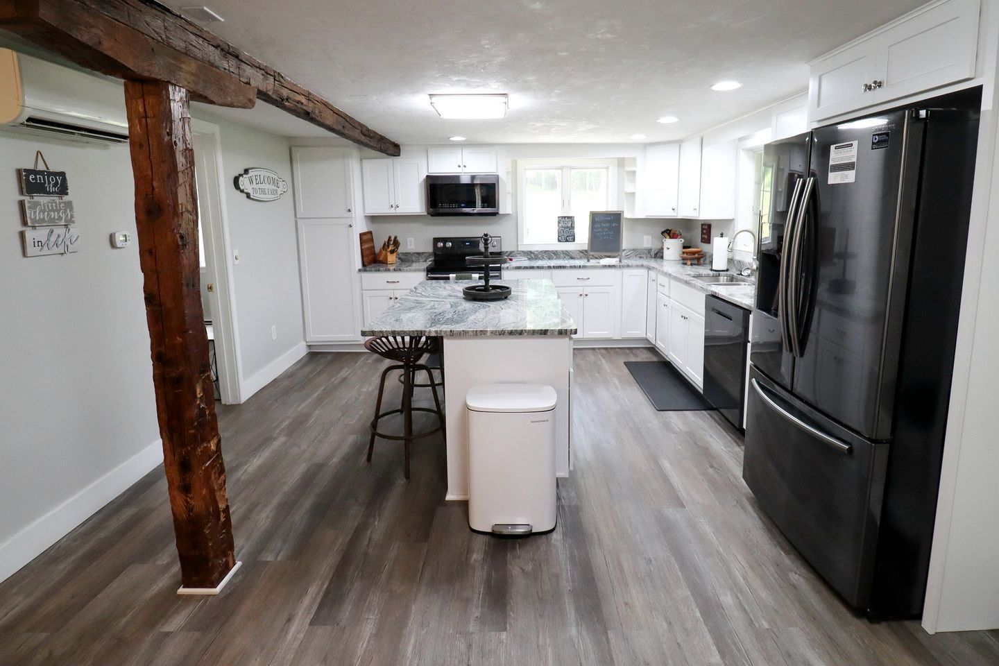 A modern kitchen with white cabinets, a black refrigerator, and a central island with stools.