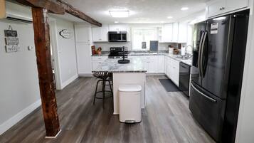 A modern kitchen with white cabinets, a black refrigerator, and a central island with stools.
