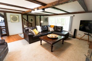 A living room with a dark brown leather sofa, a wooden coffee table, and a television on a stand.