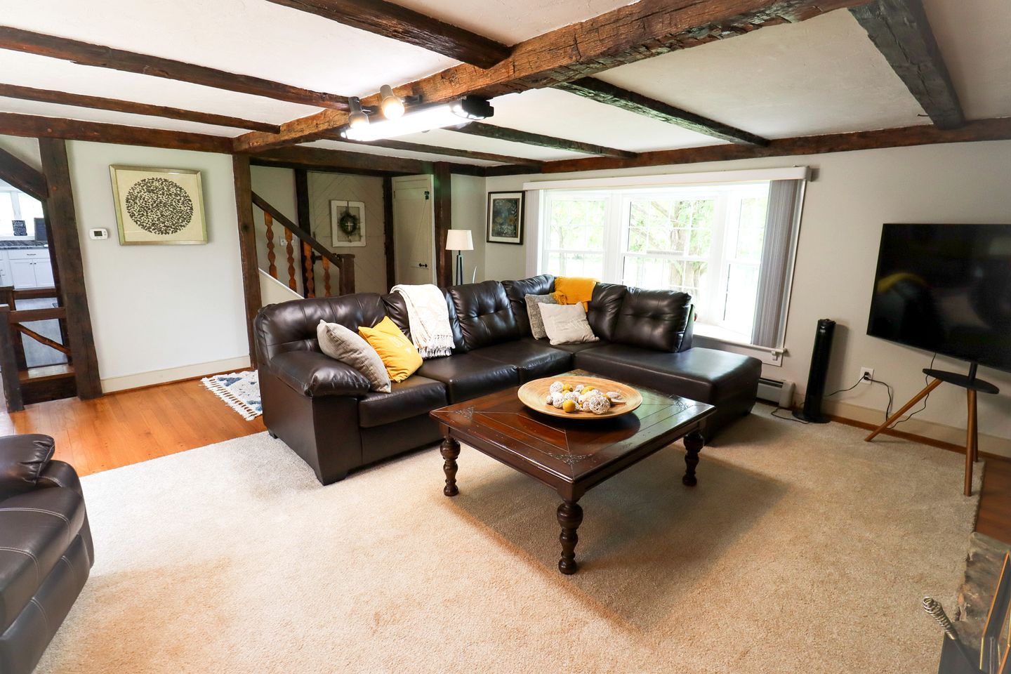 A living room with a dark brown leather sofa, a wooden coffee table, and a television on a stand.