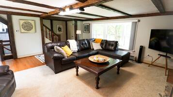A living room with a dark brown leather sofa, a wooden coffee table, and a television on a stand.