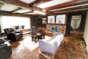 A cozy living room with a fireplace, leather sofas, and a brick wall.
