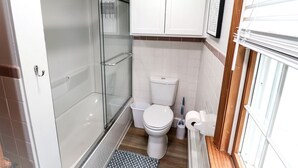 Een badkamer met een douche met glazen wand, een toilet en een bidet.