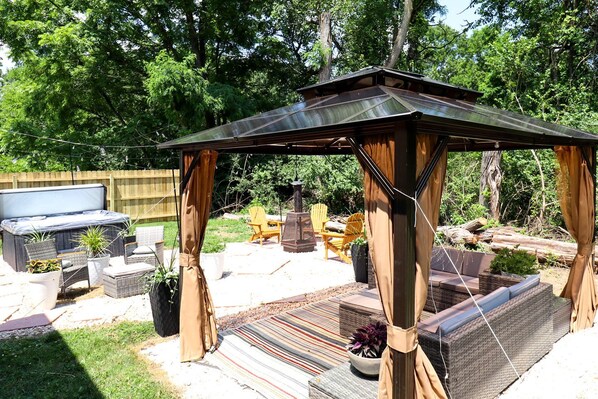 A backyard with a pergola, outdoor seating, and a hot tub.