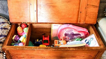 A wooden chest filled with various toys and a pink notebook.