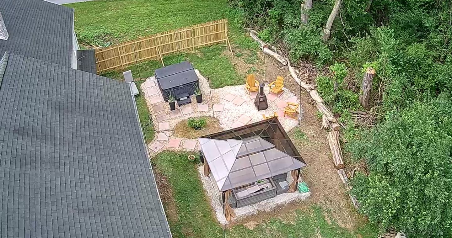 A backyard with a barbecue area, outdoor seating, and a small shed.