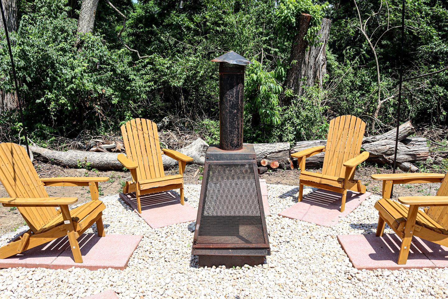 Un área de estar con cuatro sillas Adirondack de madera dispuestas alrededor de un brasero.