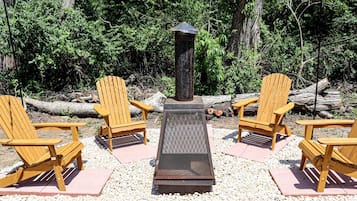 Un área de estar con cuatro sillas Adirondack de madera dispuestas alrededor de un brasero.