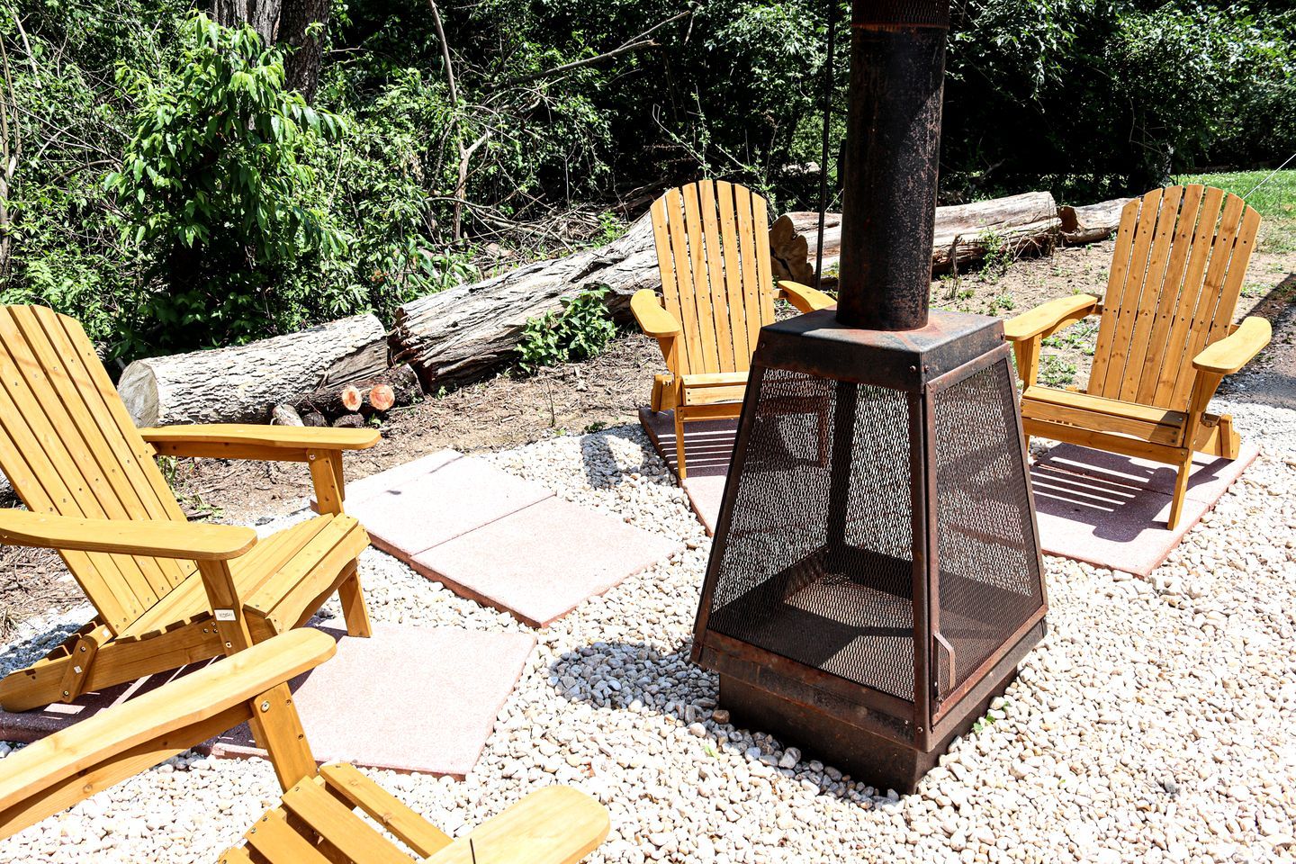 Outdoor wooden chairs arranged around a central fire pit.