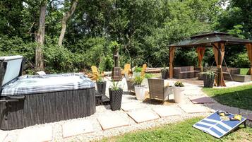 A hot tub, outdoor seating, and a pergola in a garden setting.