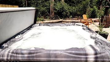 A hot tub with a wooden deck and a wooden chair in the background.