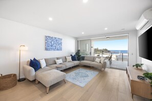 Ein modernes Wohnzimmer mit Sofa, Couchtisch und Meerblick.