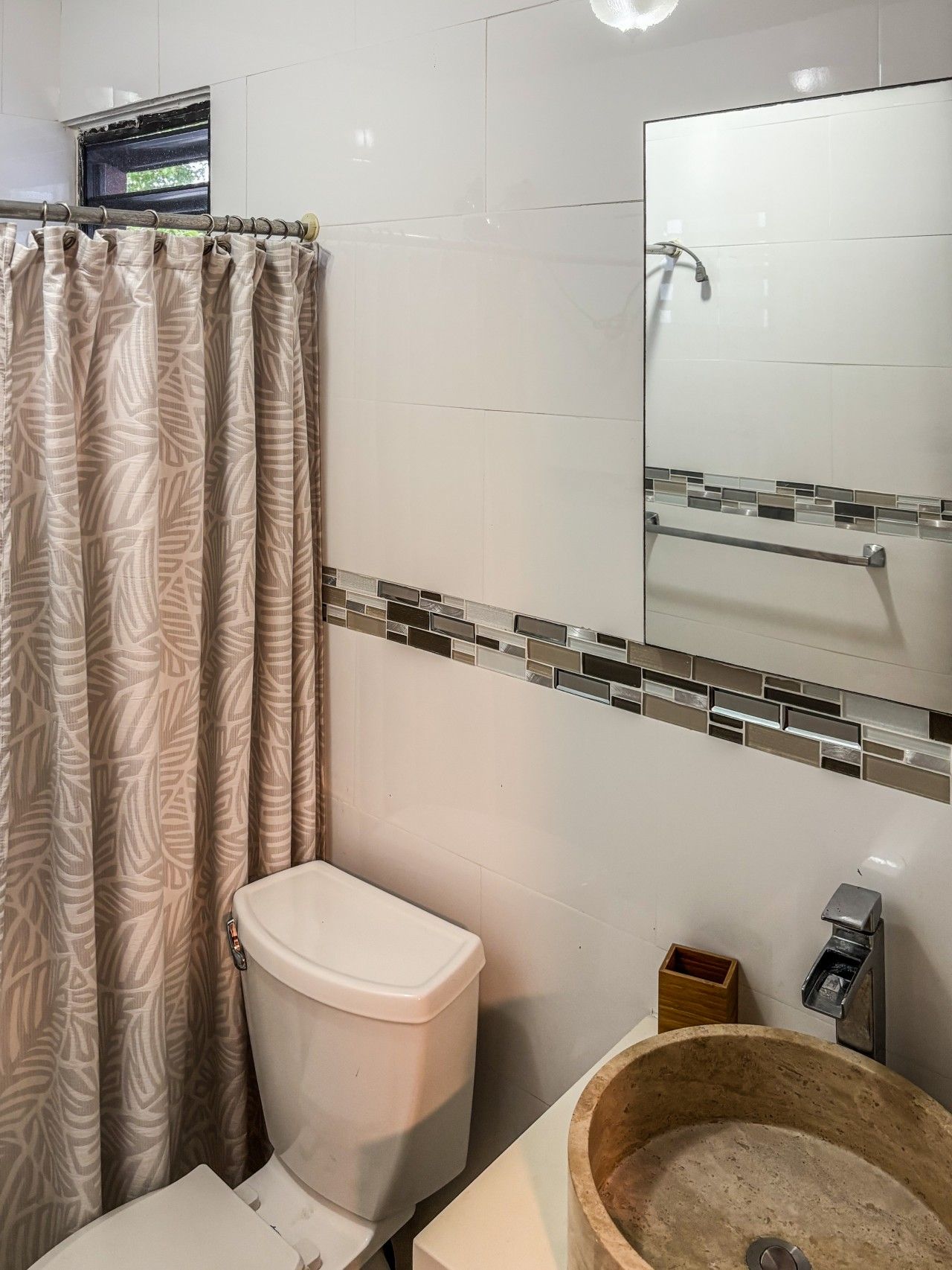 A bathroom with a toilet, a wooden basin sink, a shower with a glass door, and a mirror above the sink.