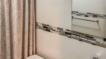 A bathroom with a toilet, a wooden basin sink, a shower with a glass door, and a mirror above the sink.