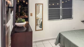 A bedroom with a bed, a dresser, a mirror, and a window with curtains.