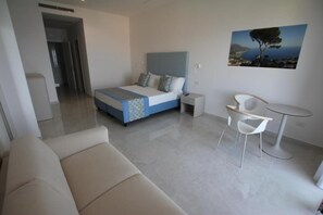 Quarto moderno com cama, mesa de cabeceira, cadeira e uma pequena mesa redonda.