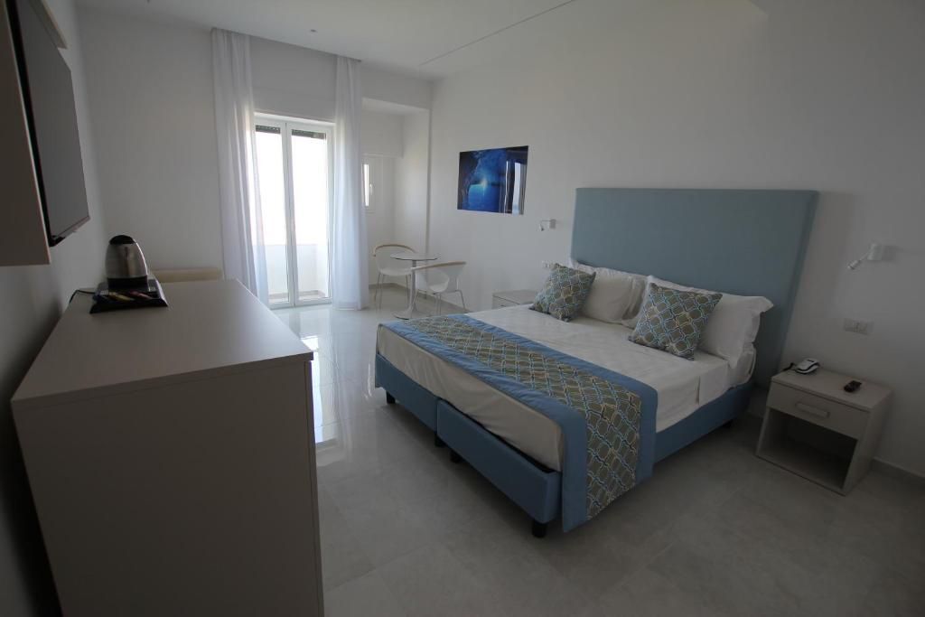 Een moderne hotelkamer met een bed, nachtkastje en een bureau met stoel.