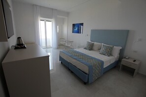 Quarto de hotel moderno com cama, mesa de cabeceira e escrivaninha com cadeira.