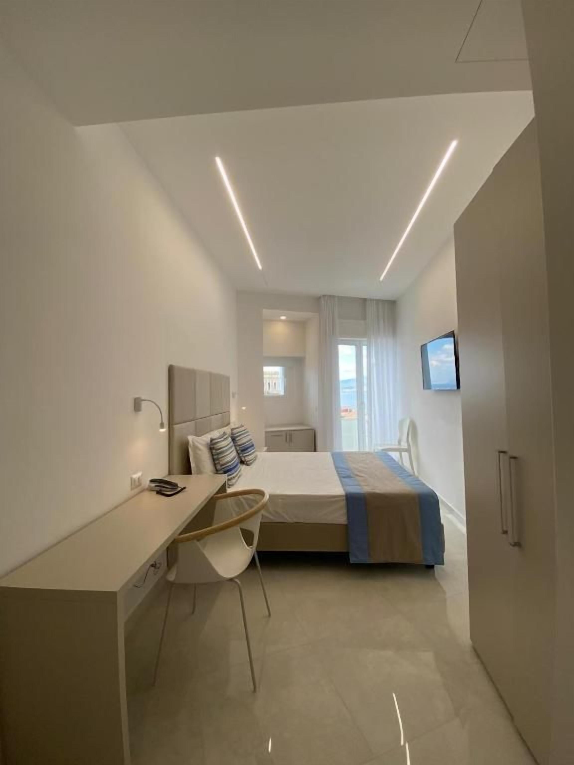 Een moderne hotelkamer met een bureau, stoel, bed en uitzicht op de stad.