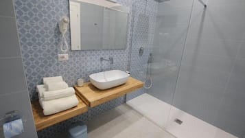 Une salle de bain avec une douche à parois de verre, un meuble-lavabo en bois avec un lavabo blanc et un miroir au-dessus du lavabo.