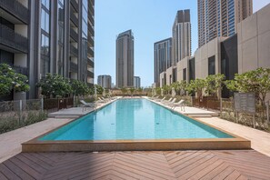 Una piscina con sillones de descanso y un deck con diseño en patrón de espiga.