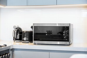 A kitchen with a microwave oven, a toaster, and a kettle on a countertop. - StayShort - Stylish 4-Bedroom Oasis  in Peaceful Creek Harbour! (Dubai Creek Harbour)