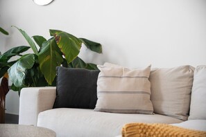 Un sofá con varios cojines, una planta en maceta y un reloj de pared.