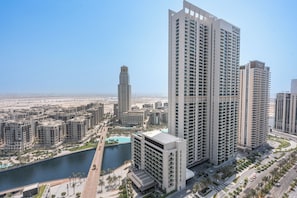 A high-rise building with multiple balconies, a pool, and a view of a river. - StayShort - Stylish 4-Bedroom Oasis  in Peaceful Creek Harbour! (Dubai Creek Harbour)