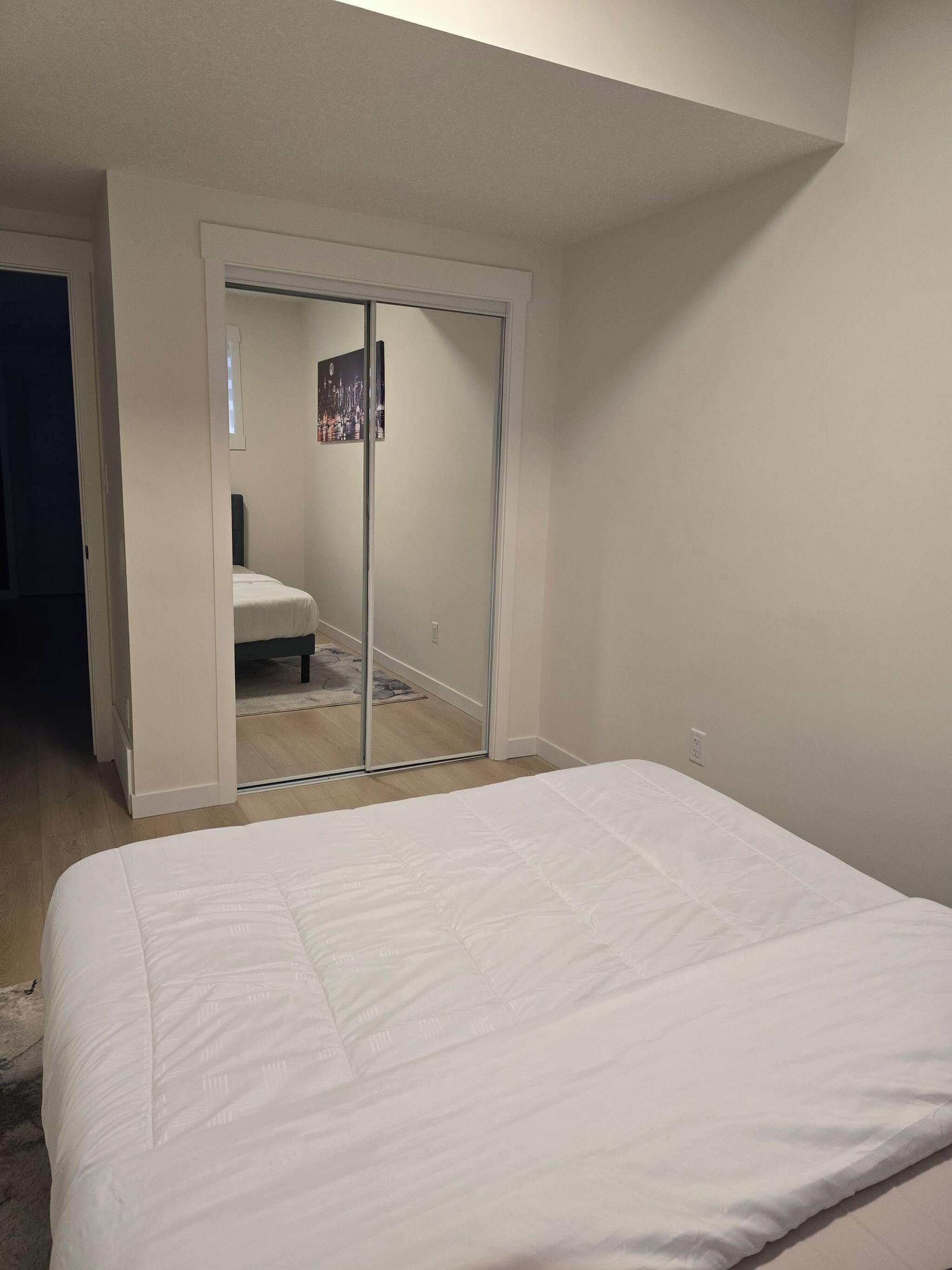 A bedroom with a bed, a sliding door closet, and a small window.