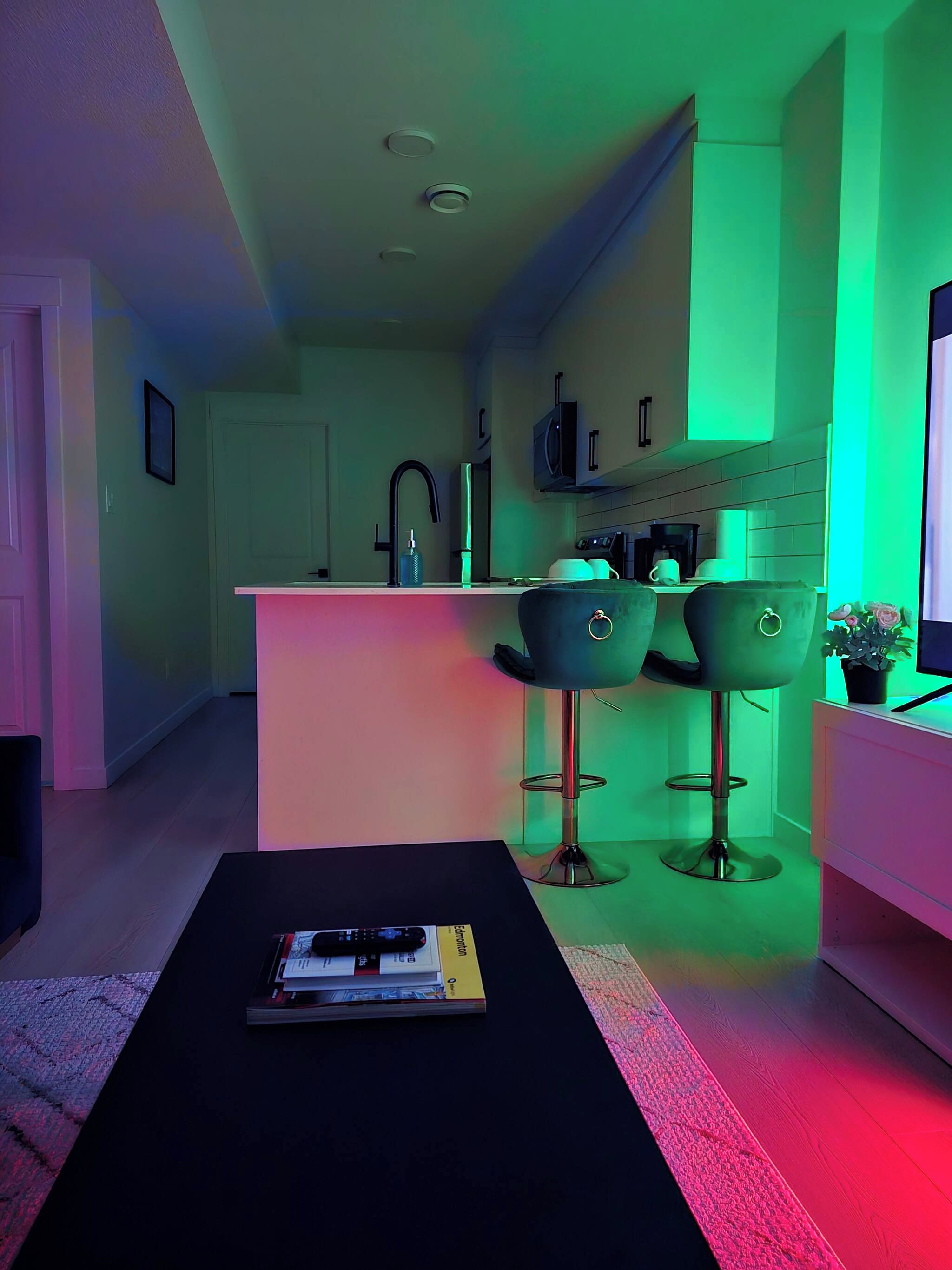 Una cocina moderna con barra, una mesa de comedor y sillas, y un televisor.