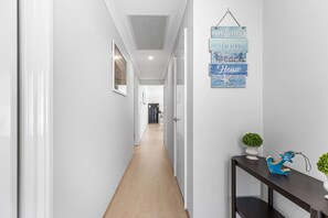 A hallway with a wooden floor, white walls, and a hanging sign that reads 'Welcome to our Beach House.' - Alkimos Coastal Escape (Alkimos)