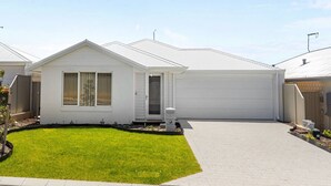 A single-story residential house with a front garage, a well-maintained lawn, and a clear sky. - Alkimos Coastal Escape (Alkimos)