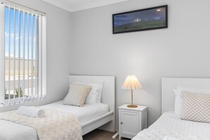 A hotel room with two beds, a television mounted on the wall, and a window with blinds. - Alkimos Coastal Escape (Alkimos)