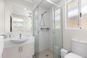A modern bathroom with a glass-enclosed shower, a white sink, and a toilet. - Alkimos Coastal Escape (Alkimos)